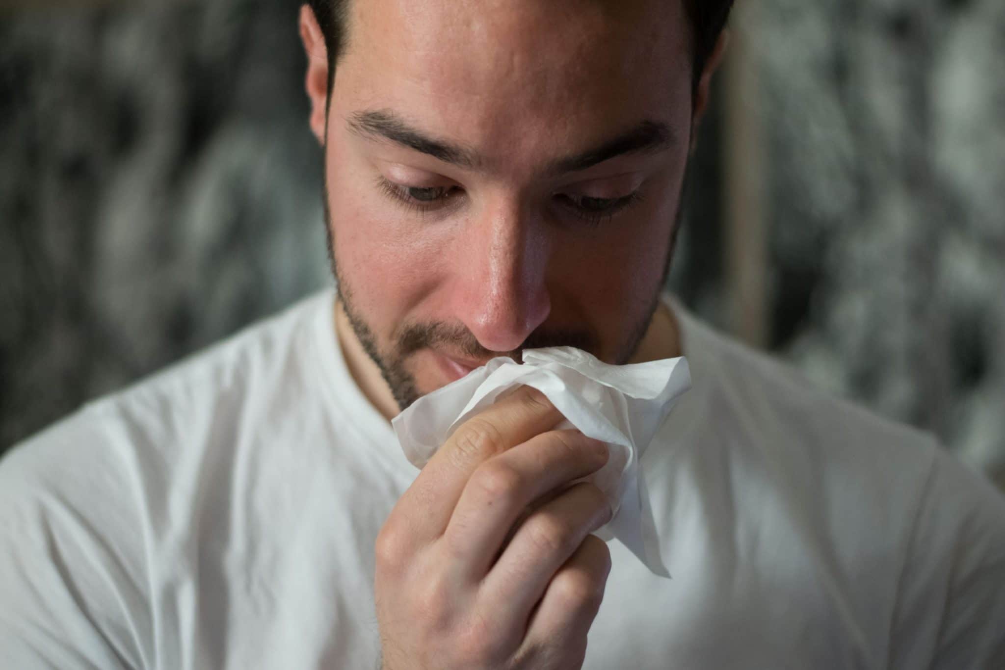 man holding tissue to nose