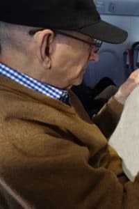 Senior man with hearing aids and reading glasses on airplane