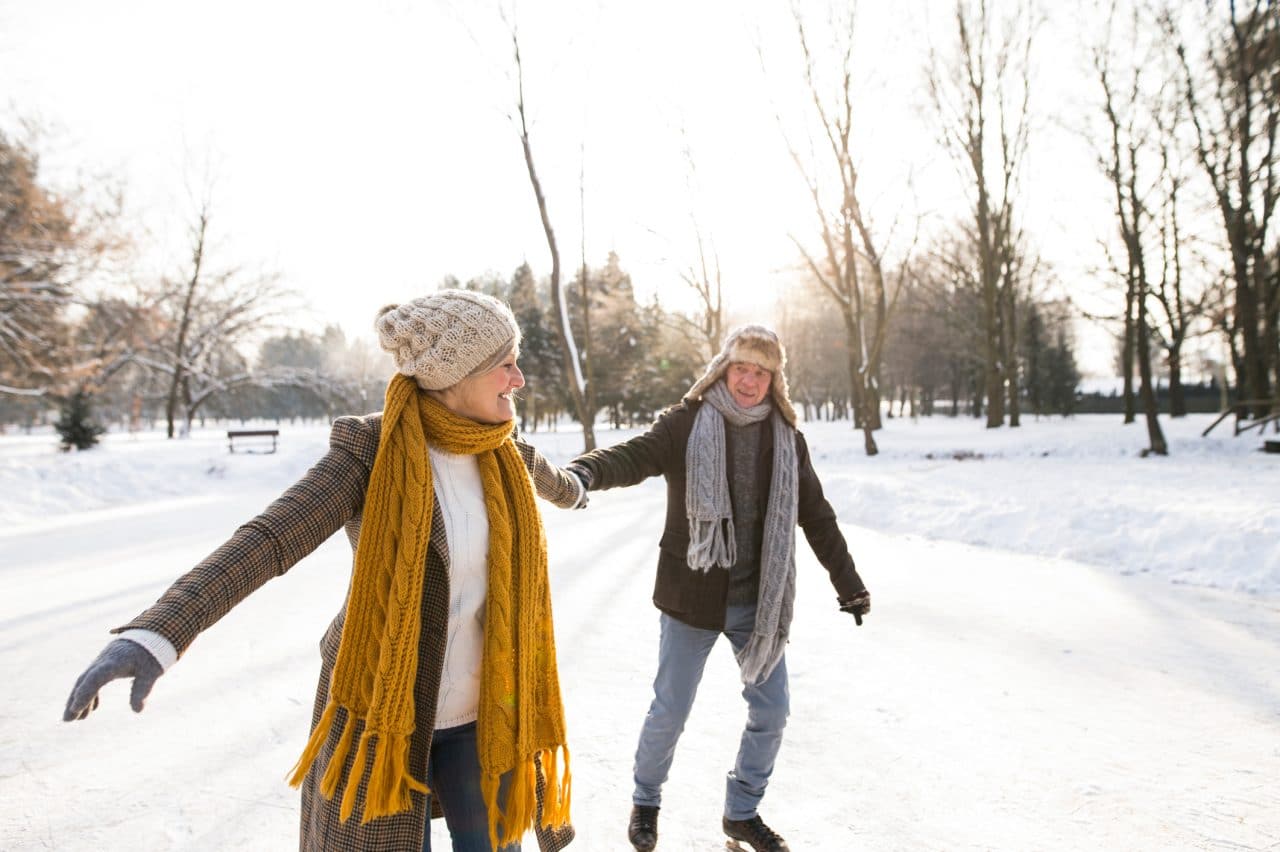 Older woman and man in sunny winter nature ice skating.