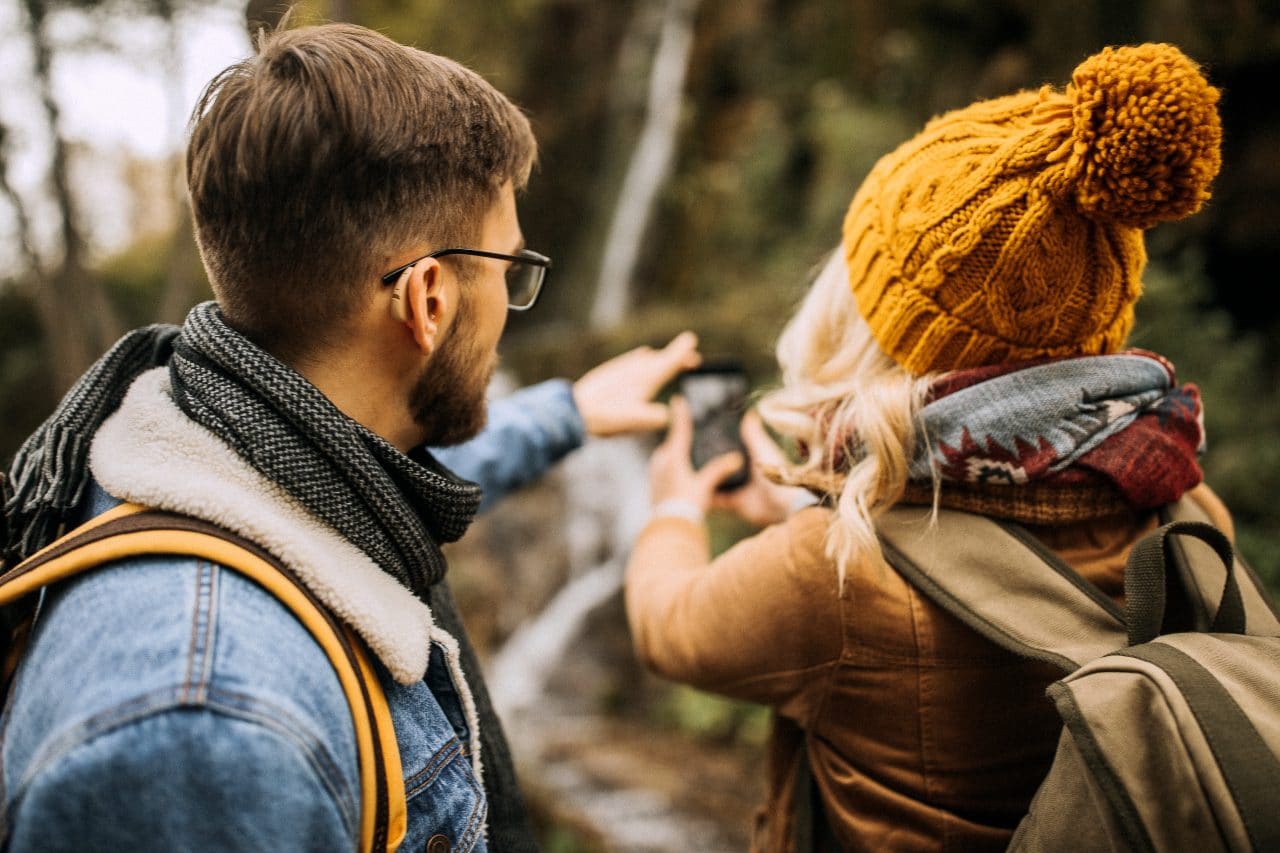 Young couple hiking. Man is wearing hearing aids.