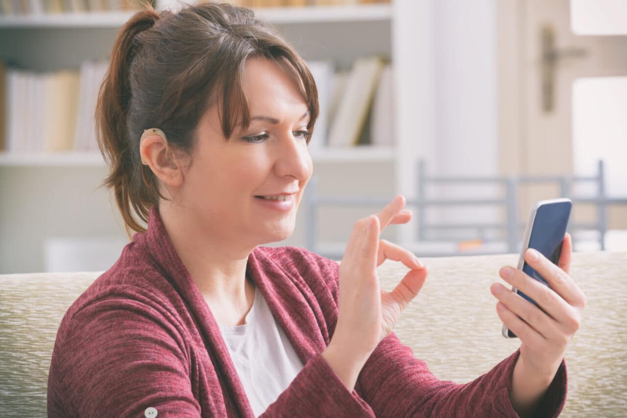 Woman with hearing aid using her smartphone.