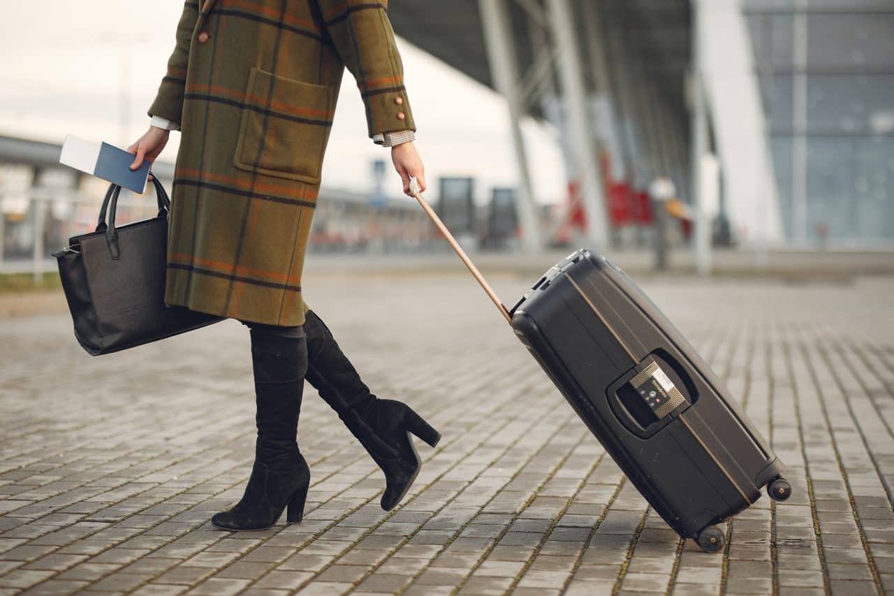 Woman carrying her bag and plane ticket as she heads into the airport.