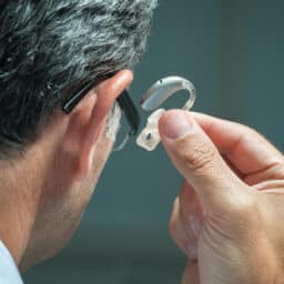Man putting on a behind-the-ear hearing aid.