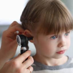 Doctor checking the inside of a little girl's ear