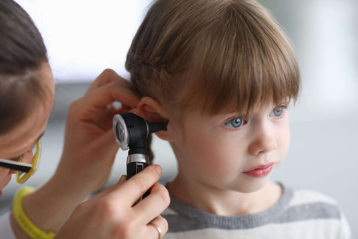 Doctor checking the inside of a little girl's ear