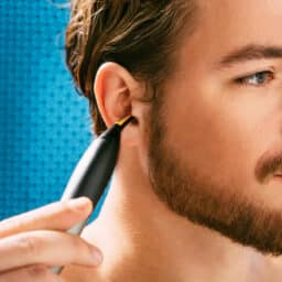 Man removes ear hair with trimmer