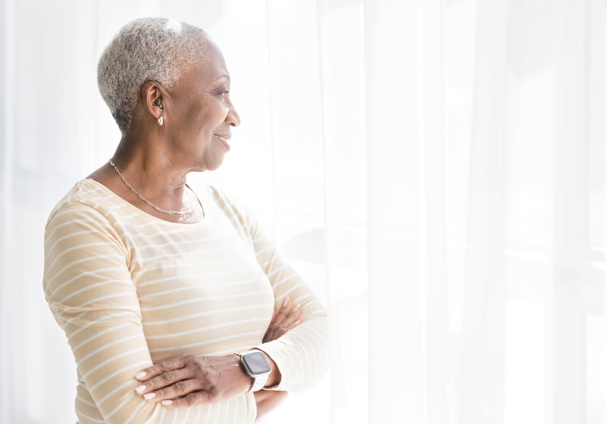 Woman with hearing aid looks out window